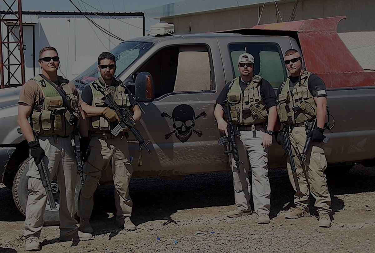 A group of men standing next to a truck.